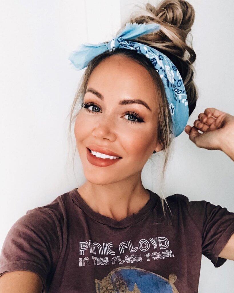 Woman with blonde hair in a high top knot wearing a blue headband.
