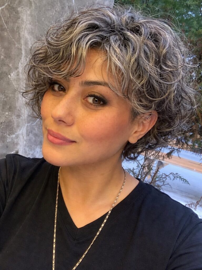 Woman with short curly layered hair in a blend of gray and brown.
