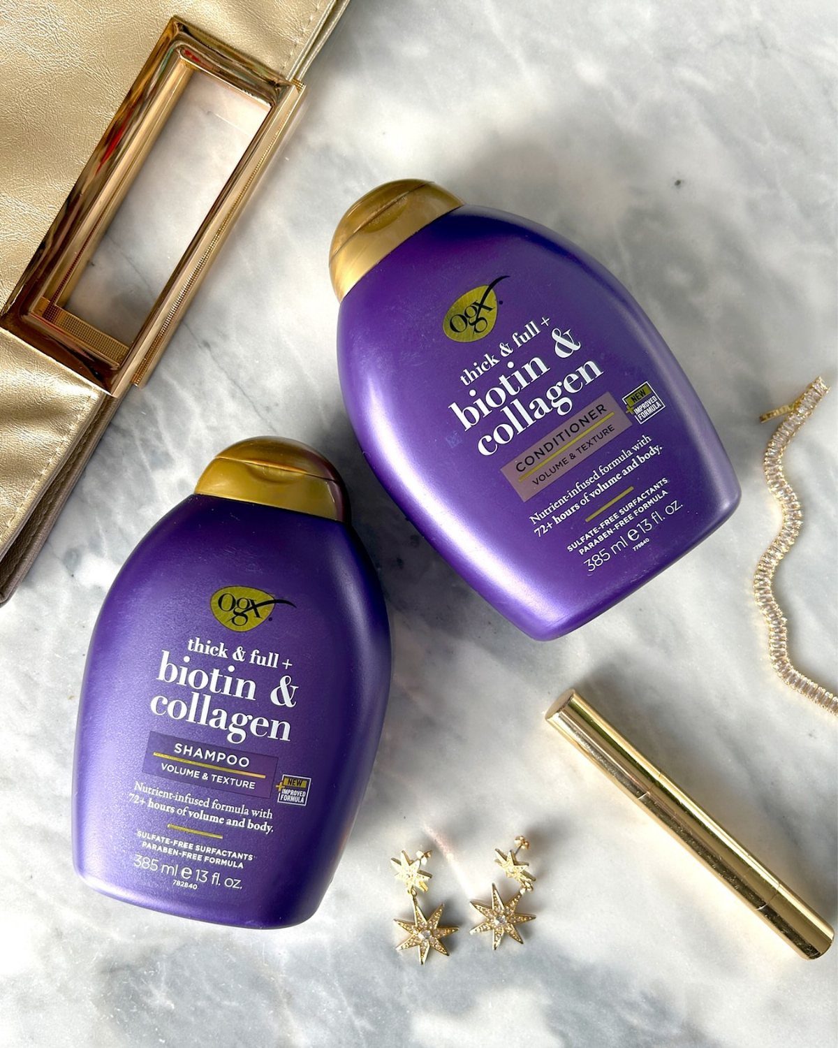 Purple OGX volumizing shampoo and conditioner bottles on a white marble surface.