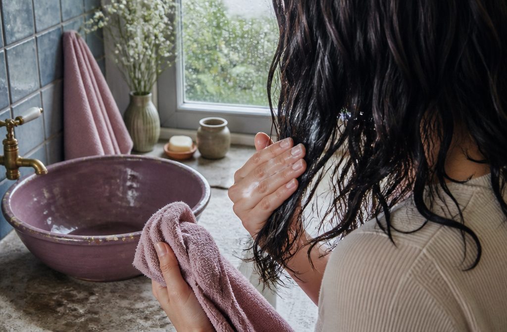 Damp hair with leave-in conditioner being applied through the lengths