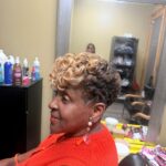 Woman with a short textured crop hairstyle featuring blonde curls on top.