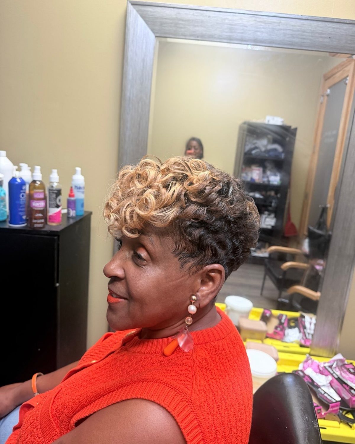 Woman with a short textured crop hairstyle featuring blonde curls on top.