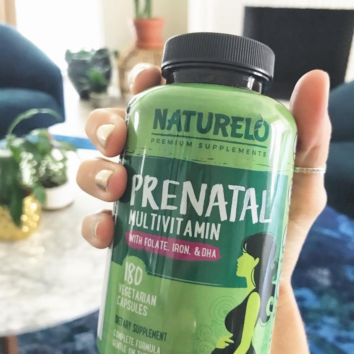 Green bottle of Naturelo Prenatal Multivitamin held by a person's hand.